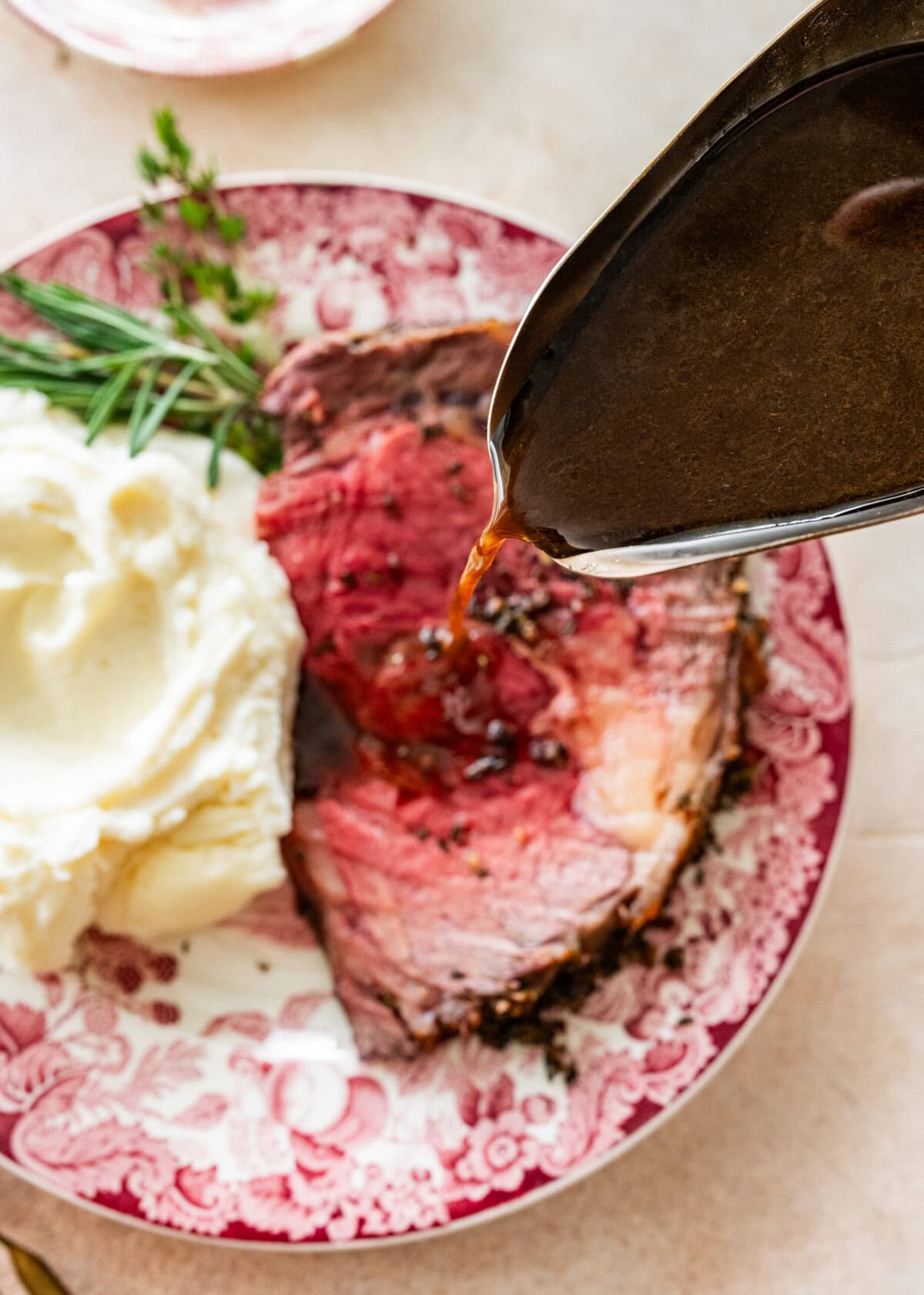 pouring au jus over the prime rib roast and mashed potatoes.