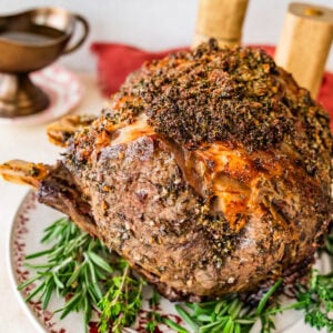 standing prime rib roast recipe on a platter with herbs around it.