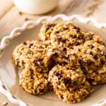 white platter with banana oatmeal cookies stacked in it. Glass of milk in the background.