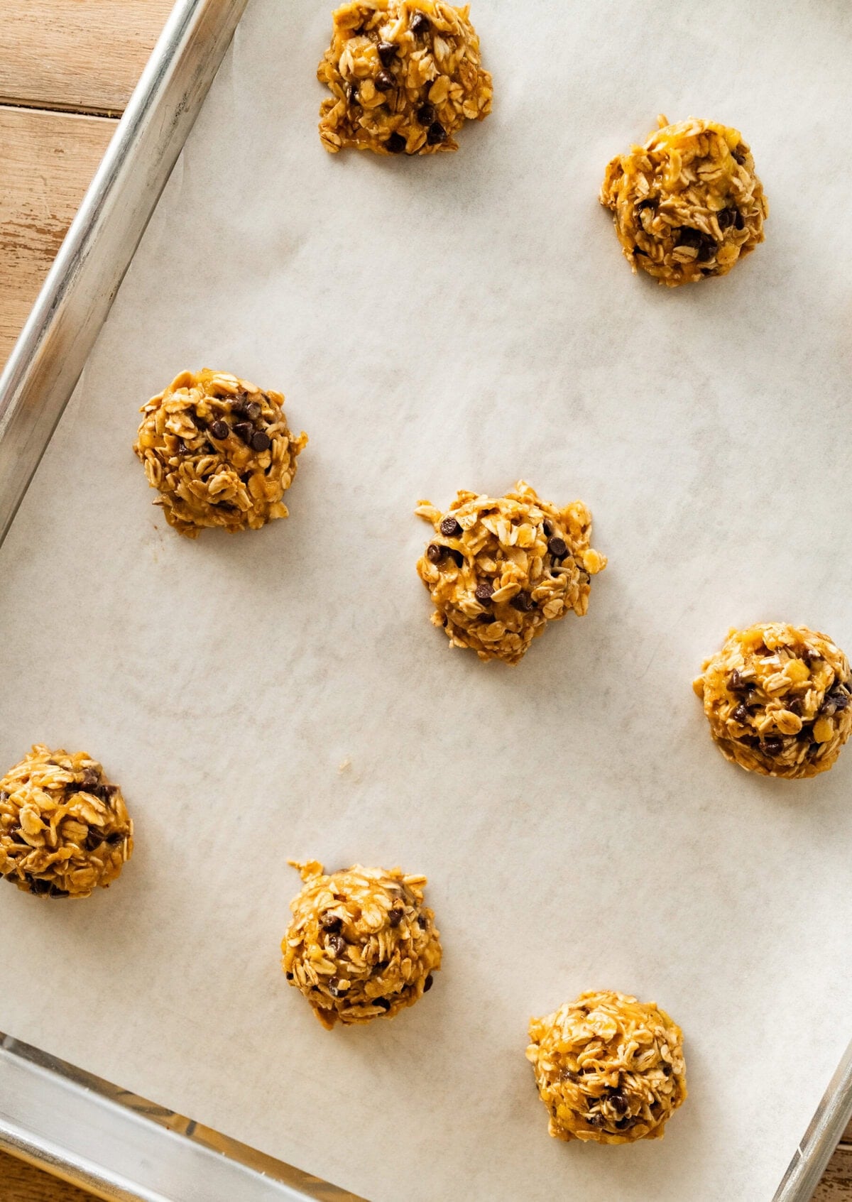 banana oatmeal cookies on a parchment lined cookie sheet ready to bake.