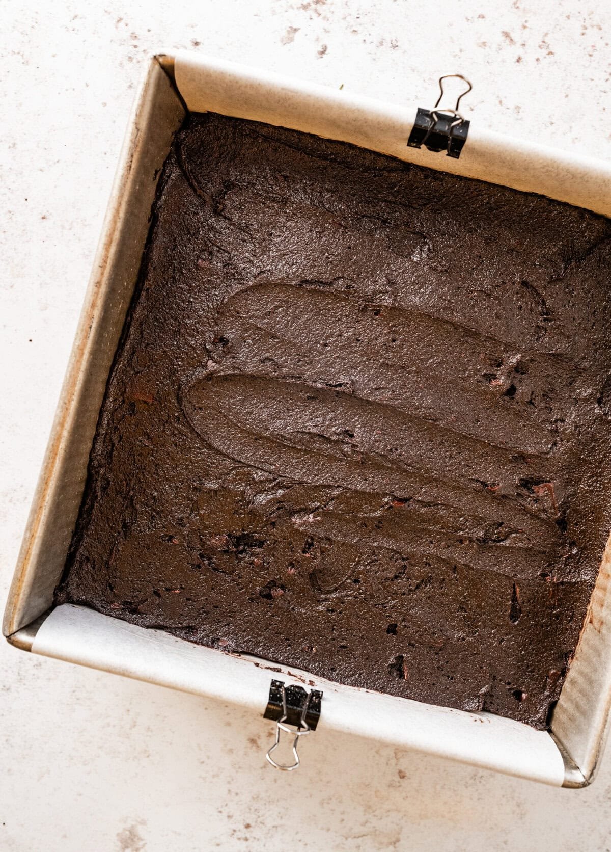 the brownie batter in a lined pan ready to bake.