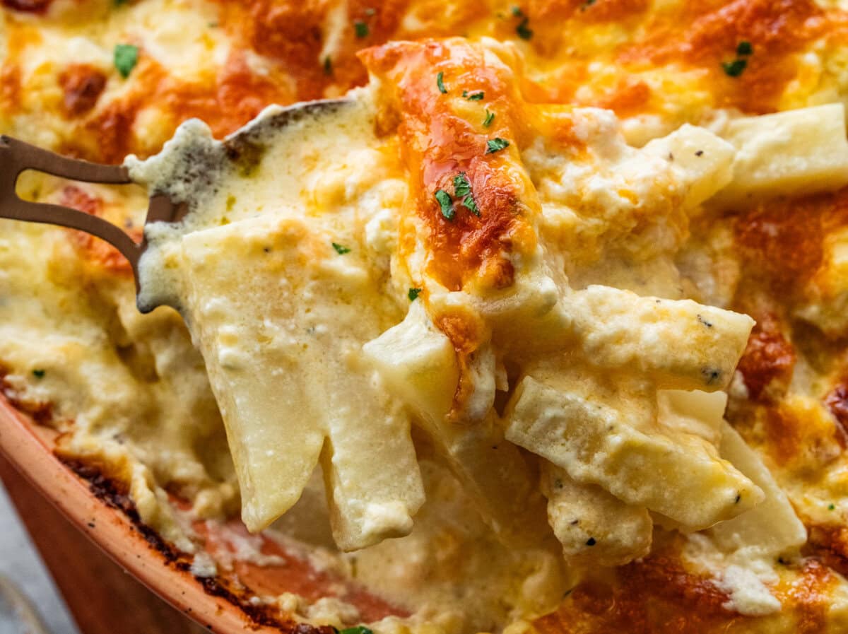 Serving spoon lifting a portion of the cheesy potatoes.
