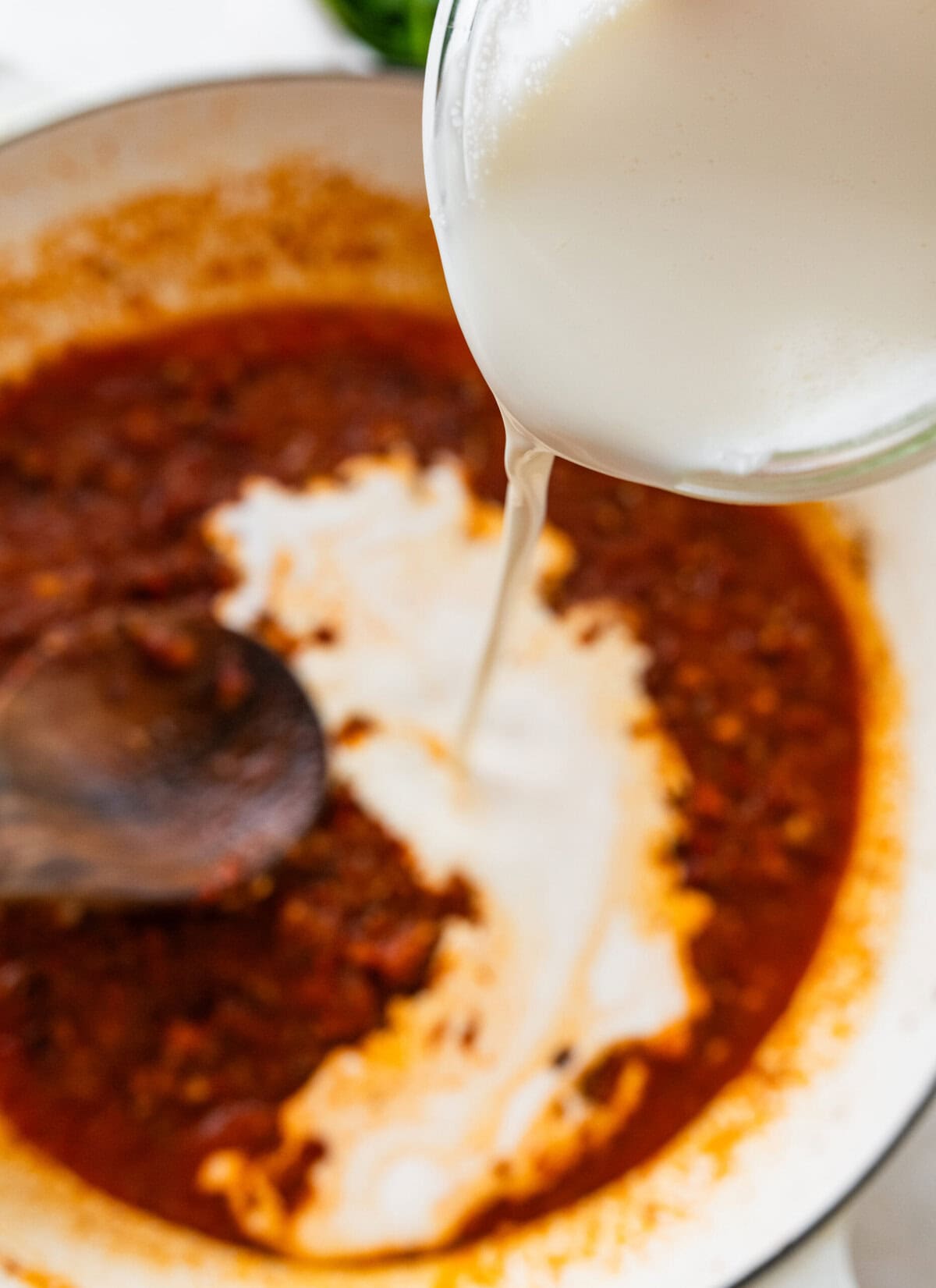 pouring cream in the pan with the red tomato sauce.