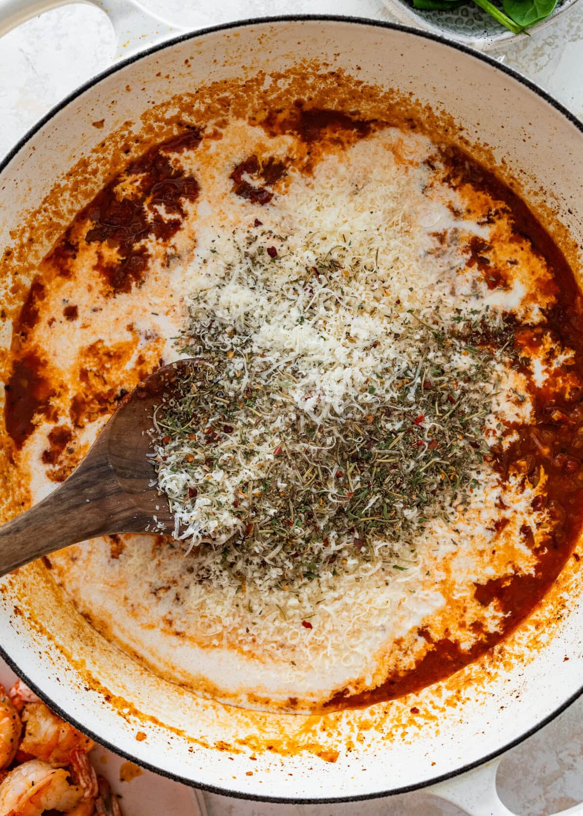 seasoning the creamy tomato marry me shrimp sauce with parmigiano cheese and herbs.