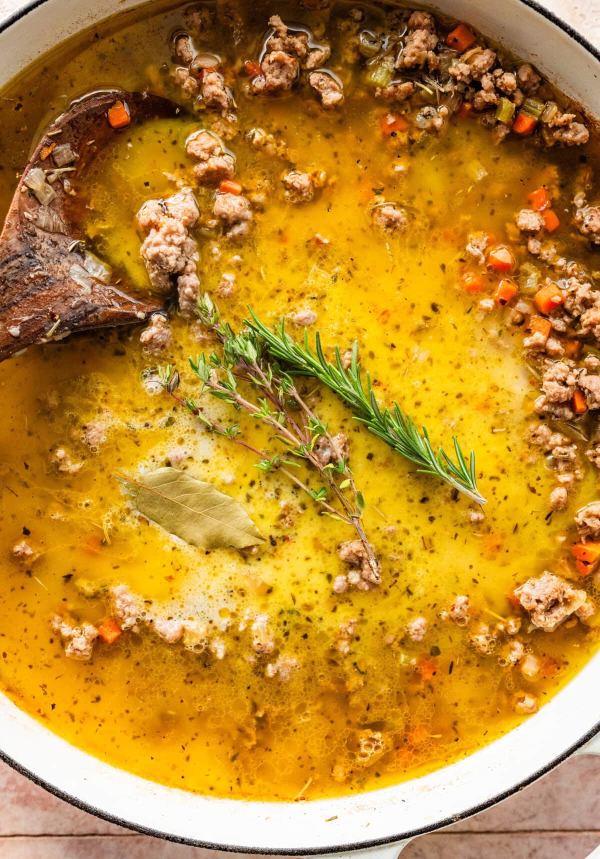 fresh thyme and rosemary in pan to simmer the white bolognese sauce.