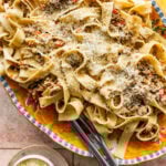 parmigiano cheese on top of white ragu pasta in a large Italian style serving platter.