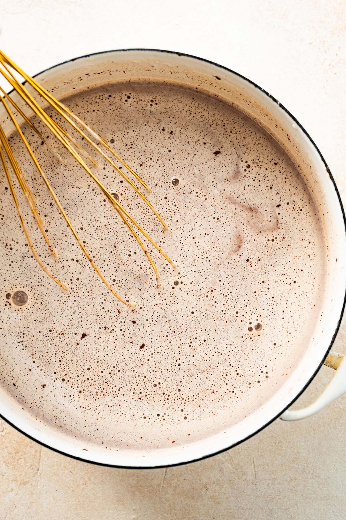 thickened hot chocolate in a pot with a whisk.