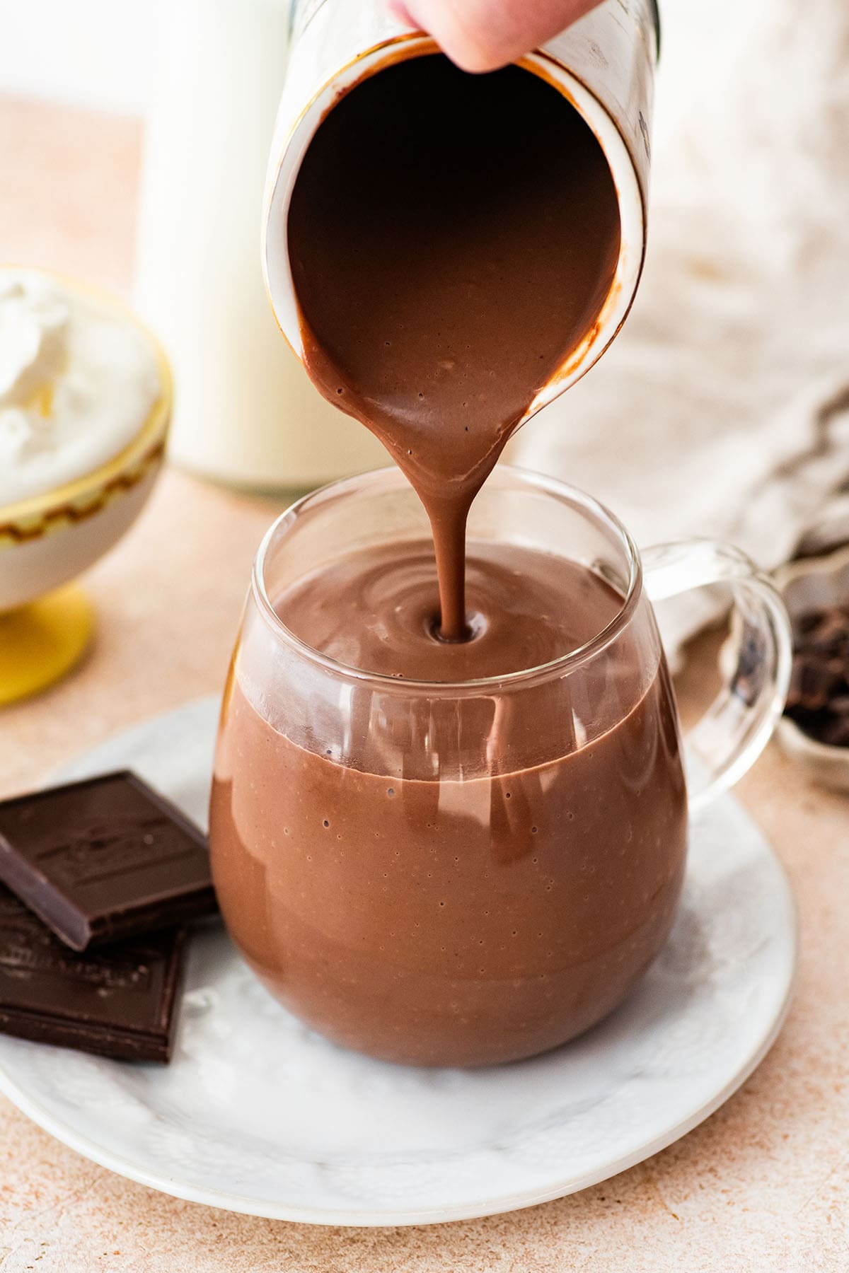 pouring thick Italian hot chocolate into a glass mug.