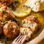 Fork holding a meatball that is cut in half.