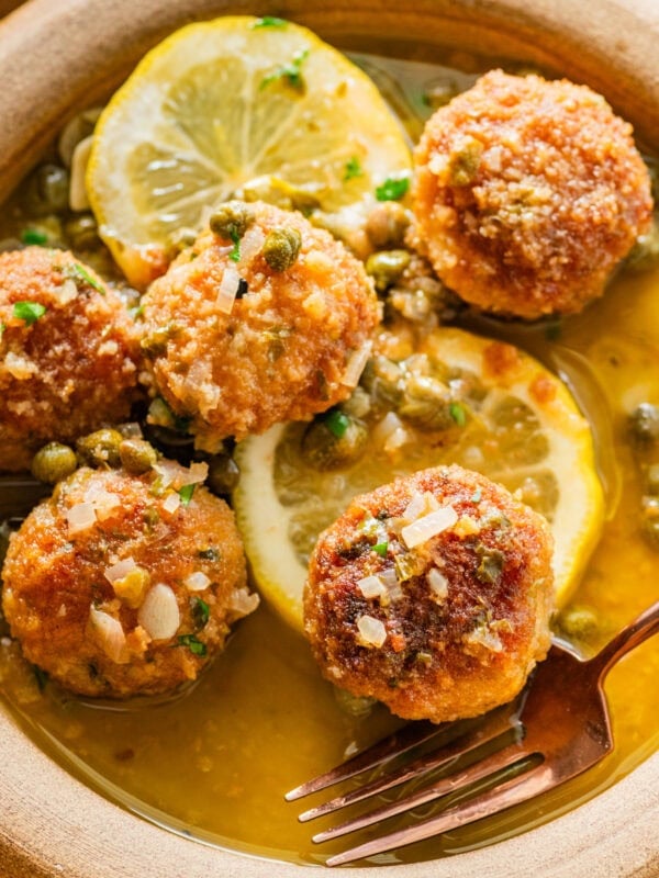 Chicken piccata meatballs in a bowl garnished with lemon.