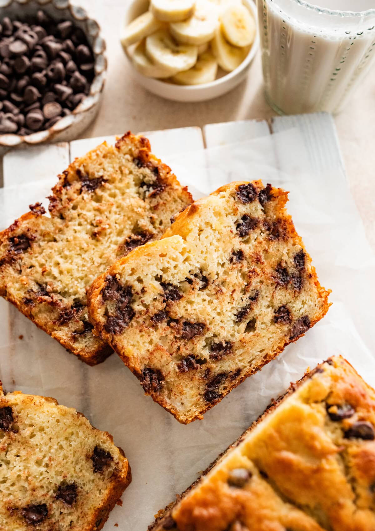 Slices of chocolate chip banana bread laid out with banana slices and chocolate chips in the background.