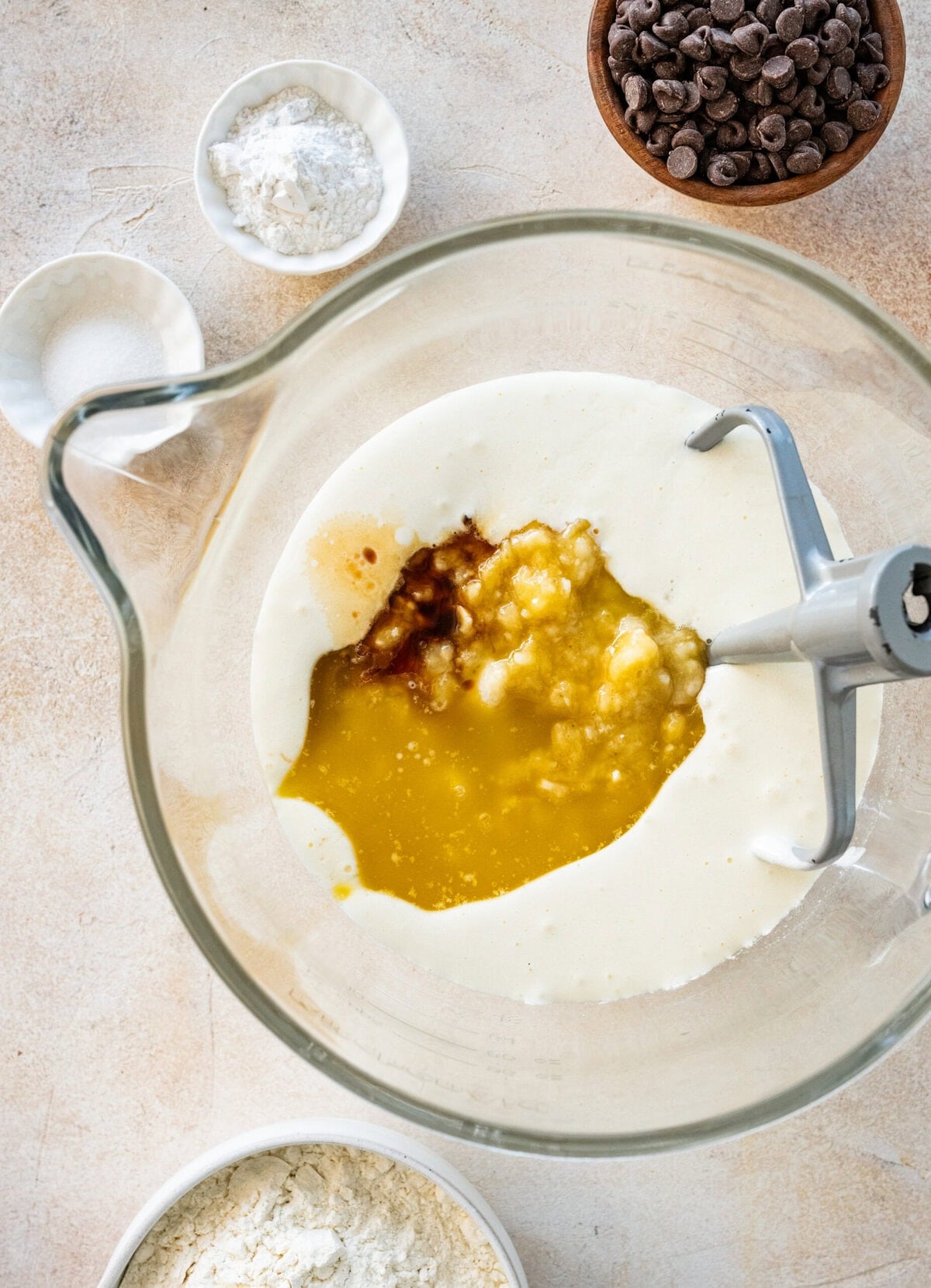 Wet ingredients to make banana bread added to the same bowl as the sugar and egg mixture.