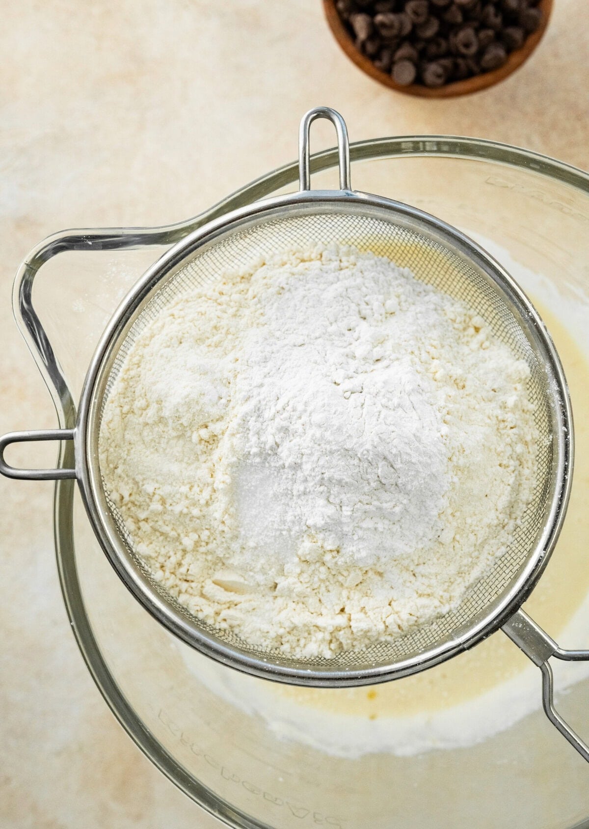 Sifting the dry ingredients for the chocolate chip banana bread over the wet ingredients.