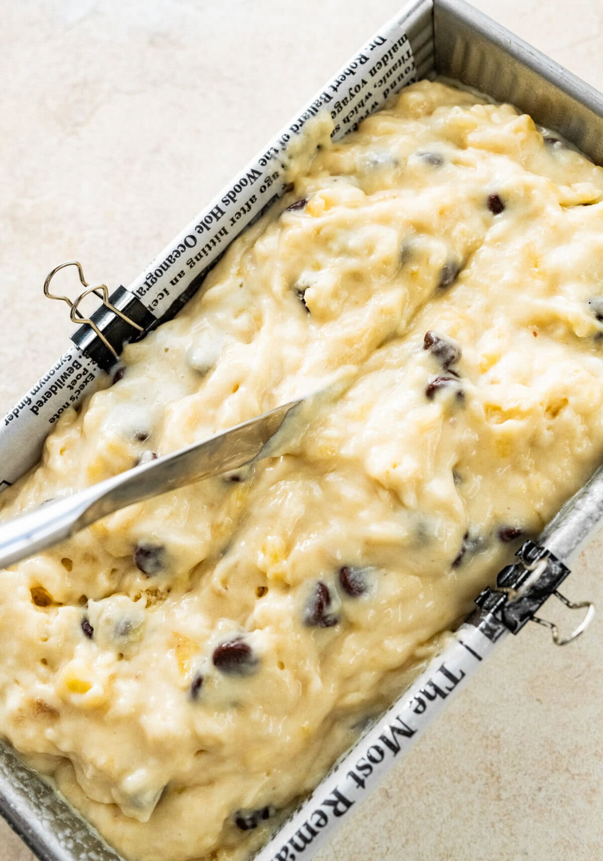 A knife scoring a slit through the top of the chocolate chip banana bread.