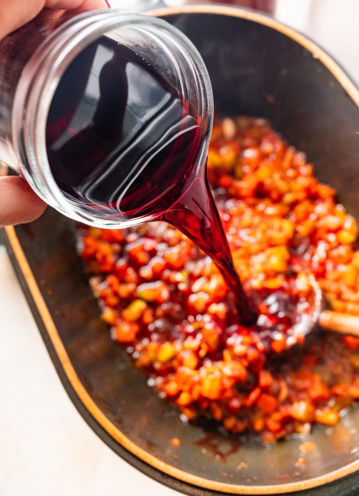Pouring red wine vinegar on top of the cooked vegetables.