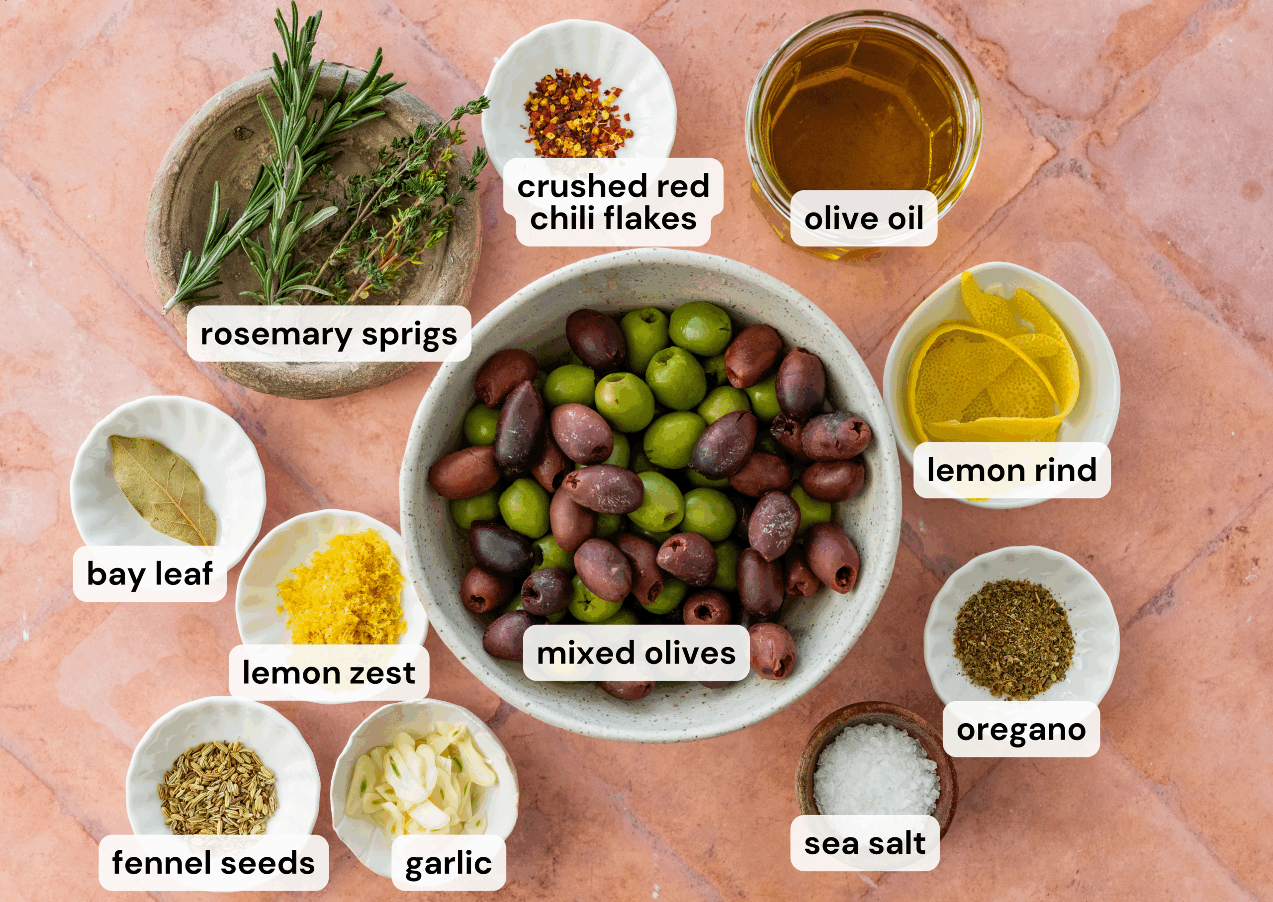 Ingredients to make marinated olives each separated in its own bowl.