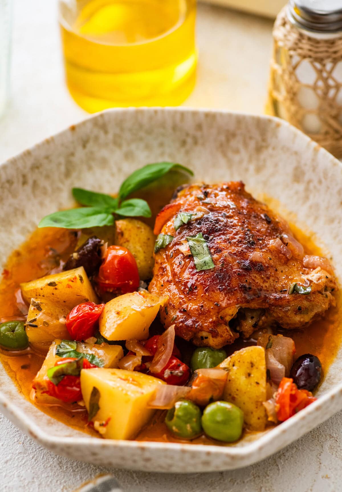 plate with a serving of baked mediterranean chicken crispy chicken and perfectly cooked potatoes and veggies.