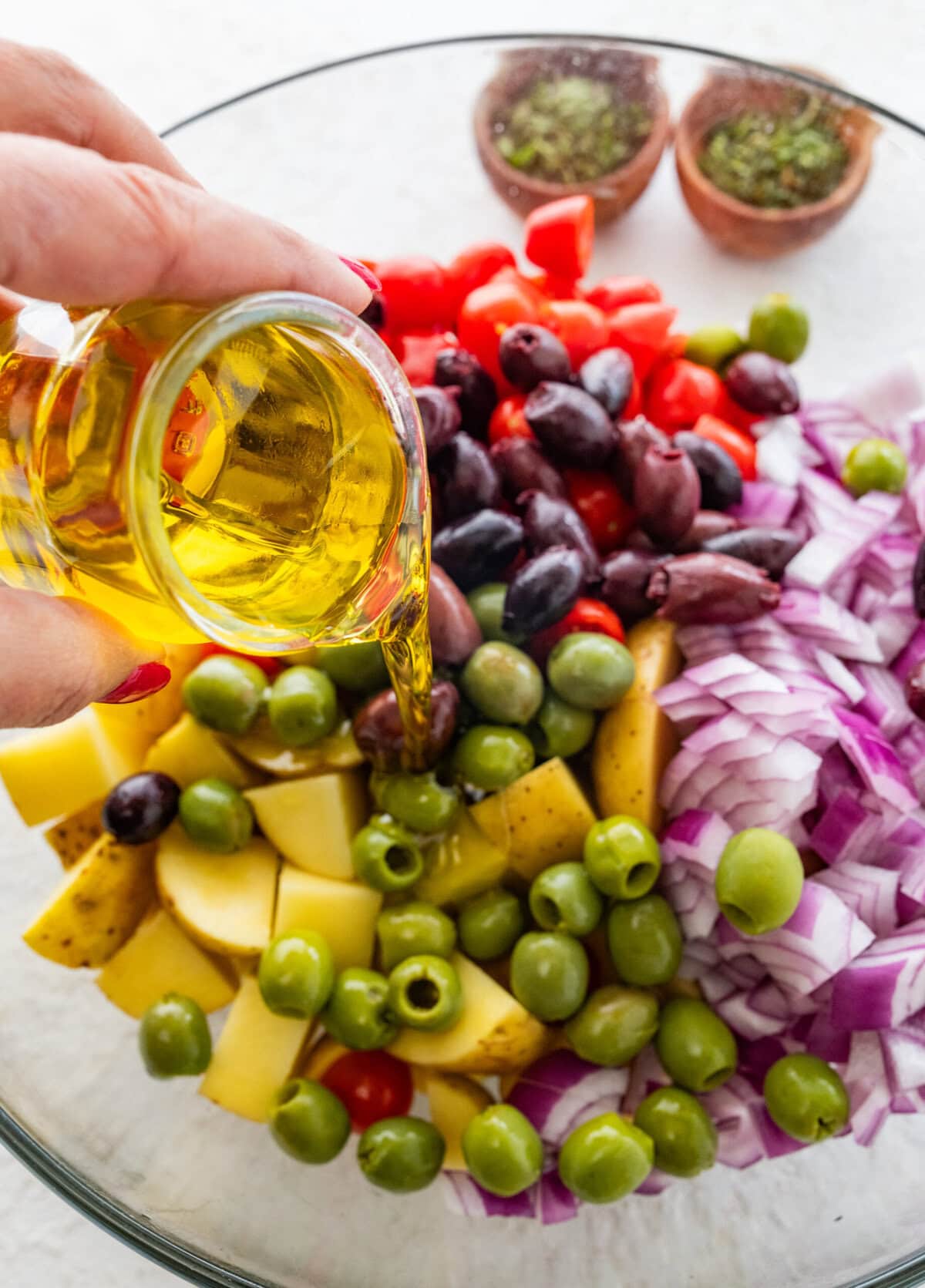 all ingredients except the chicken in a bowl hand pouring olive oil to season.