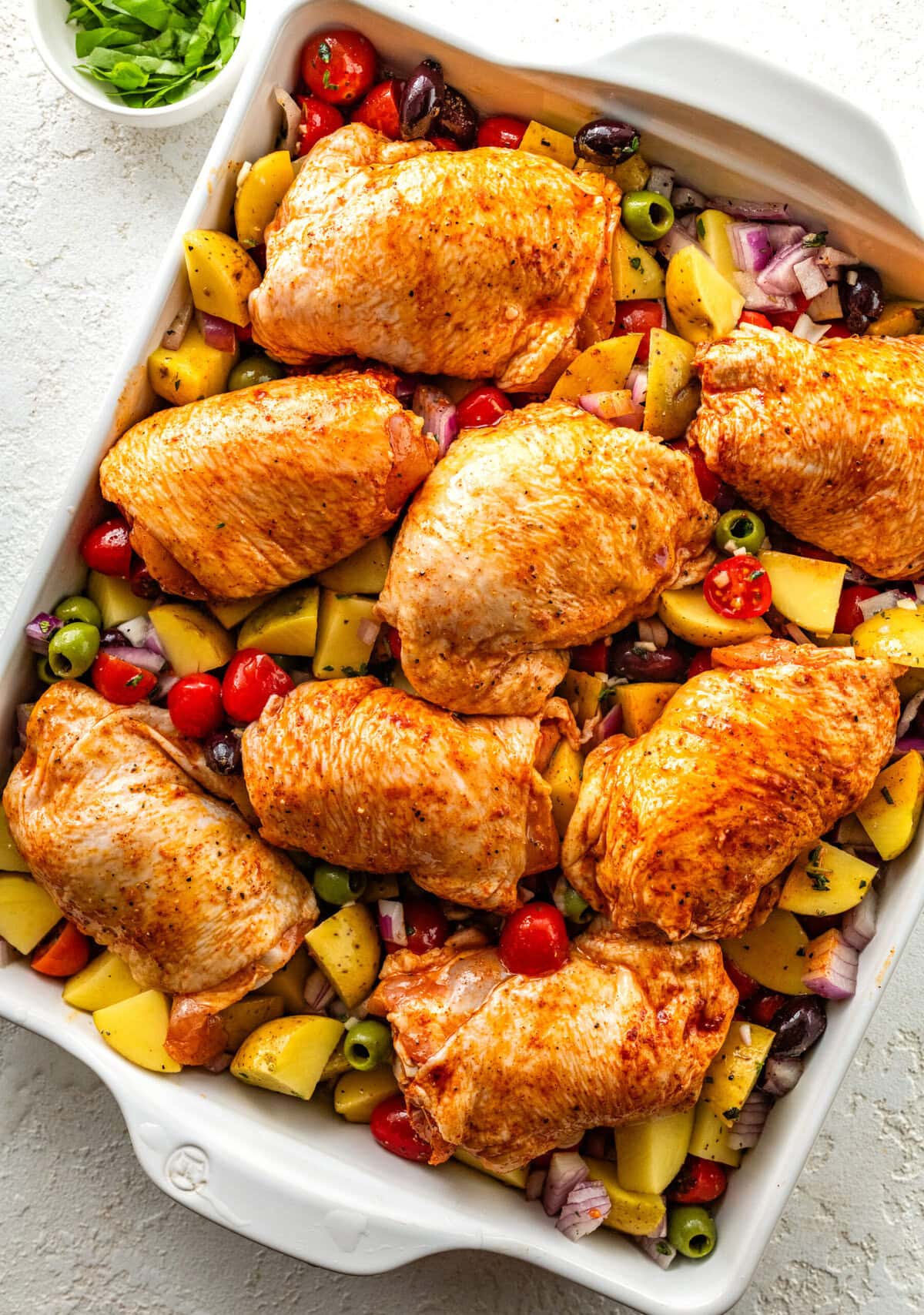 large baking pan with seasoned mediterranean chicken and veggies ready to bake.