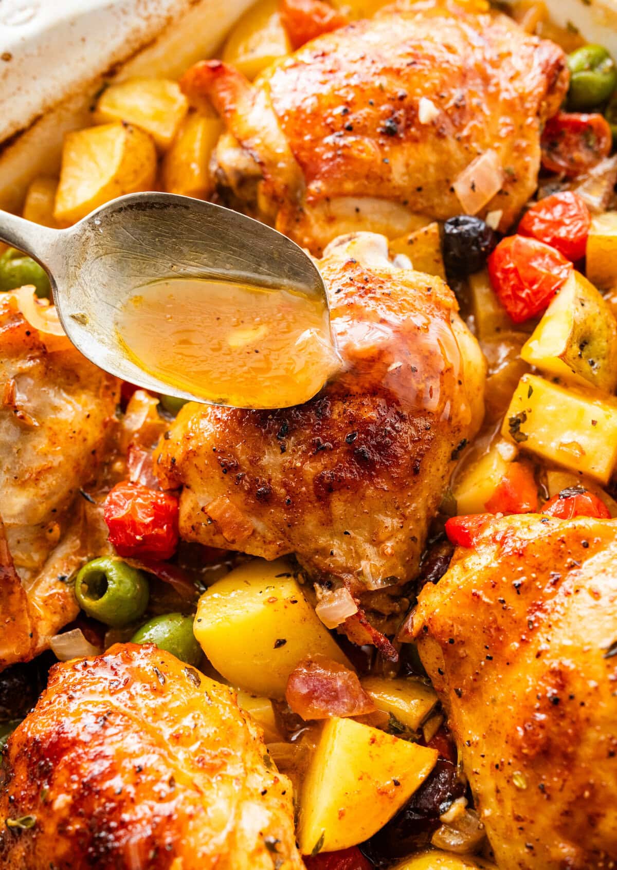 baked mediterranean chicken with spoon to pour over the yummy sauce.