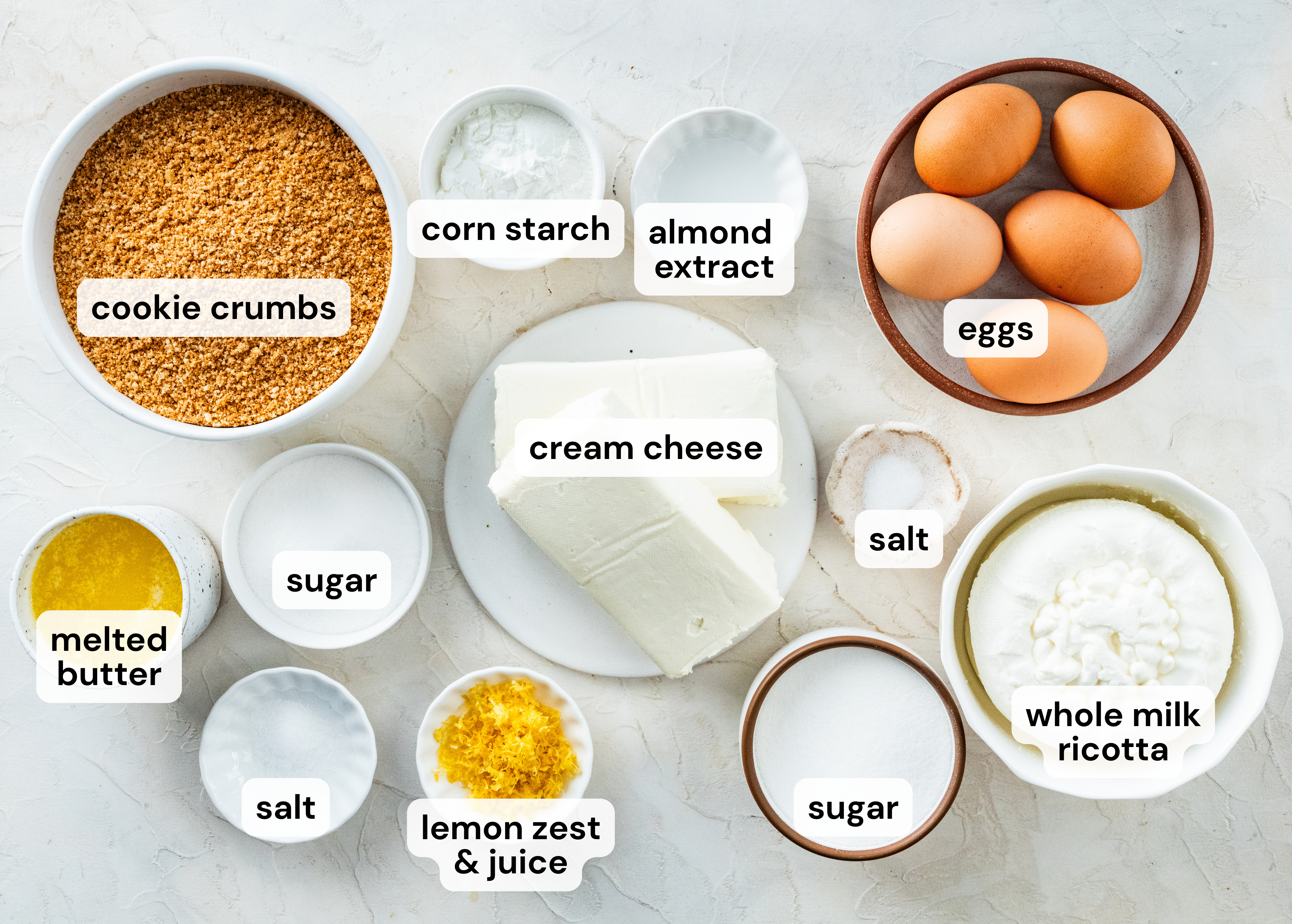 ingredients to make ricotta cheesecake recipe all in separate labeled bowls.