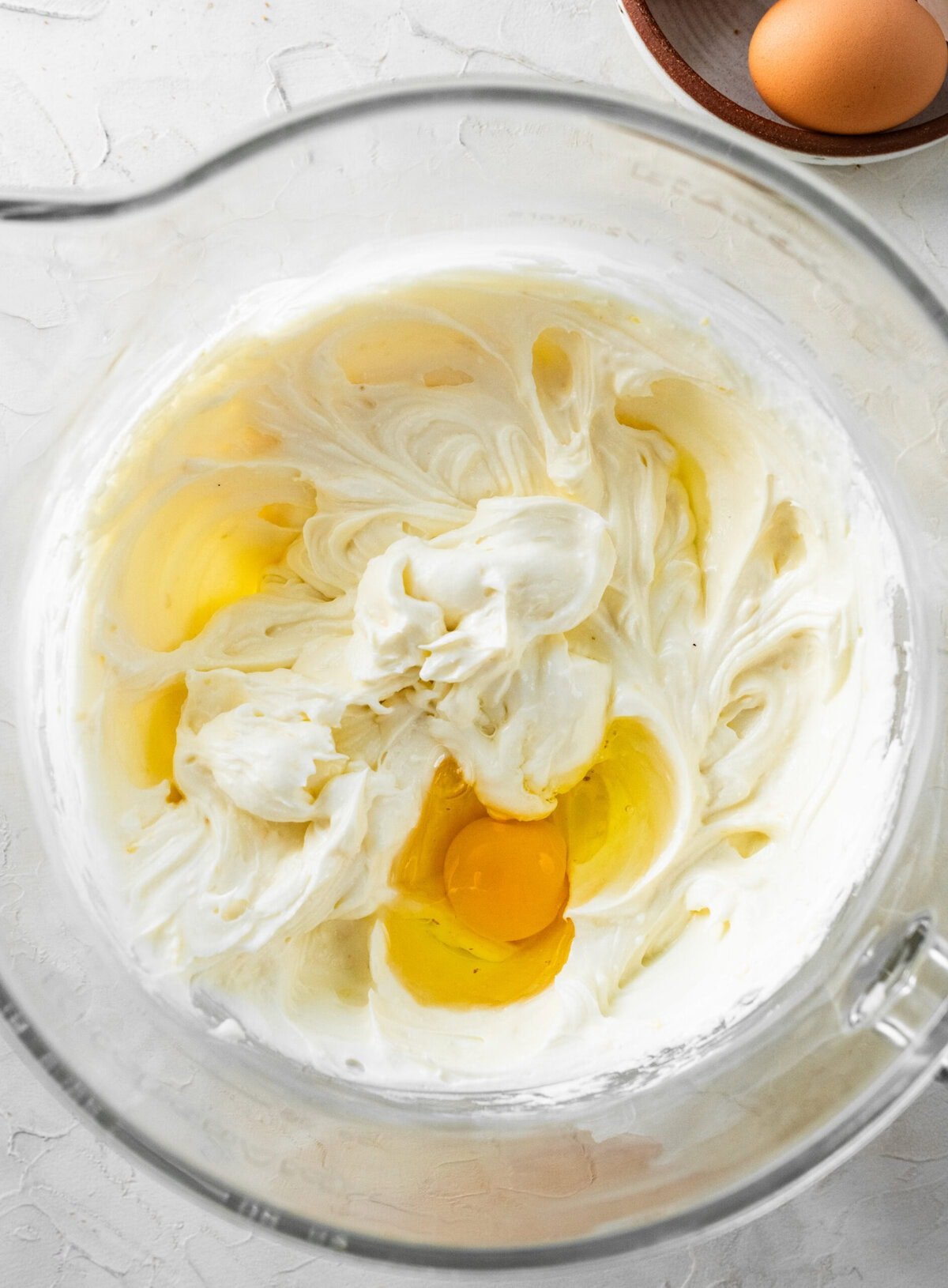 adding the egg on top of the mixed ricotta cheesecake filling.