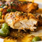 Braised chicken thigh cut in half to show inside of chicken, with more of the chicken plated in the background.