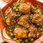 Braised chicken thighs in a bowl topped with garnish and surrounded by other ingredients.