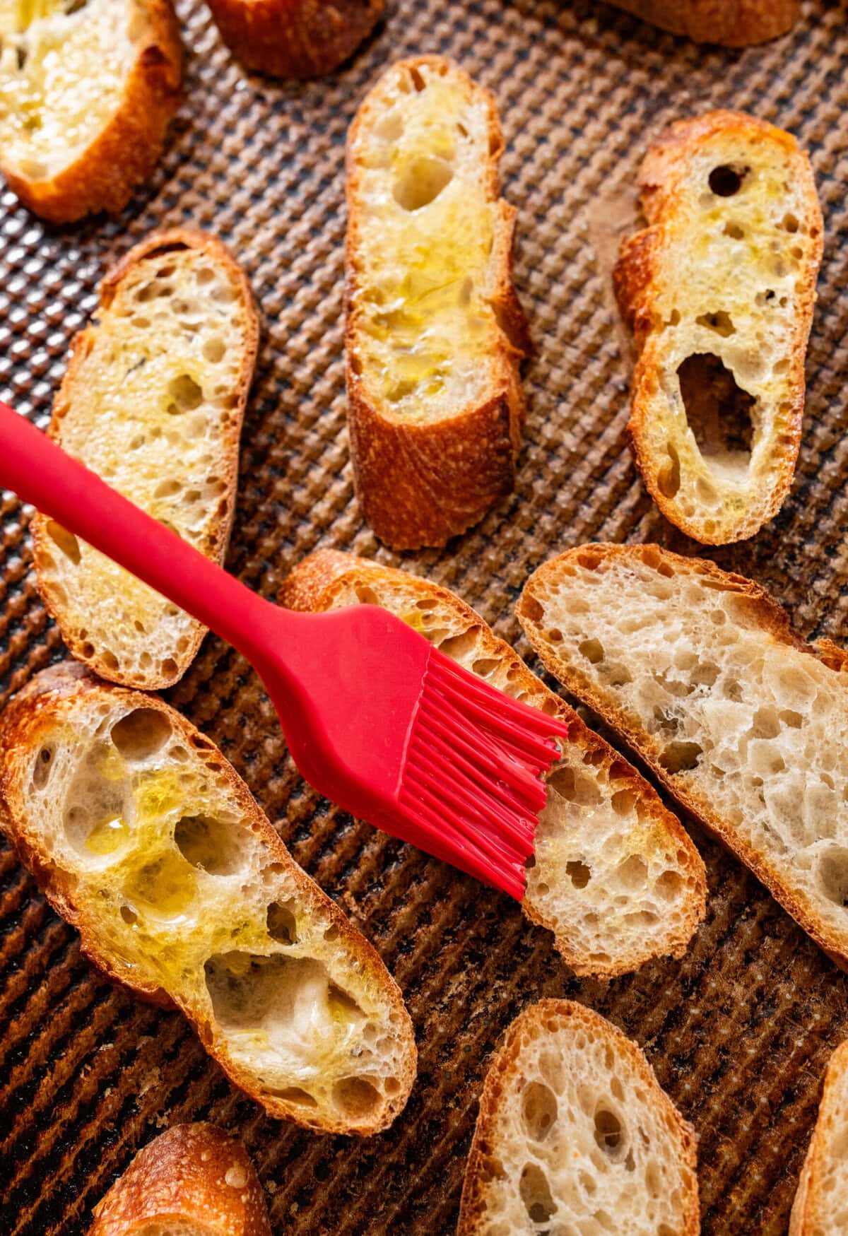 Brushing slices of bread with olive oil.