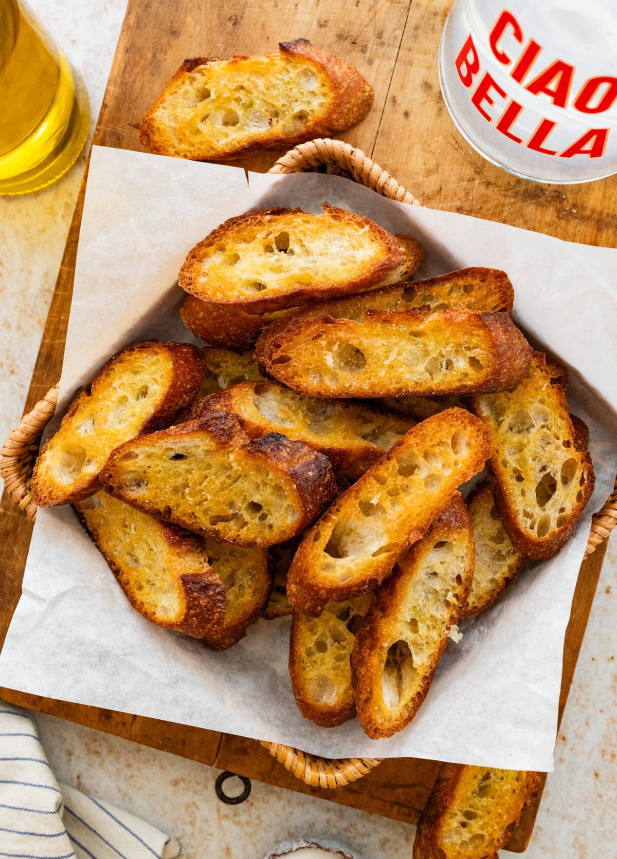 A pile of crostini on a tray with other ingredients in the background.