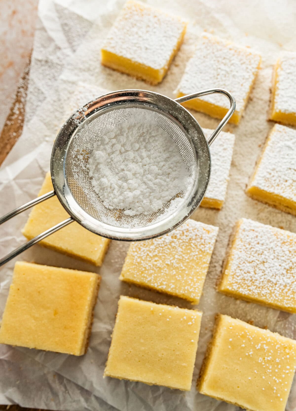 Dusting powder on top of lemon cream cheese bars.