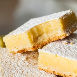 Lemon cream cheese bar with a bite taken out, laying on top of more bars.