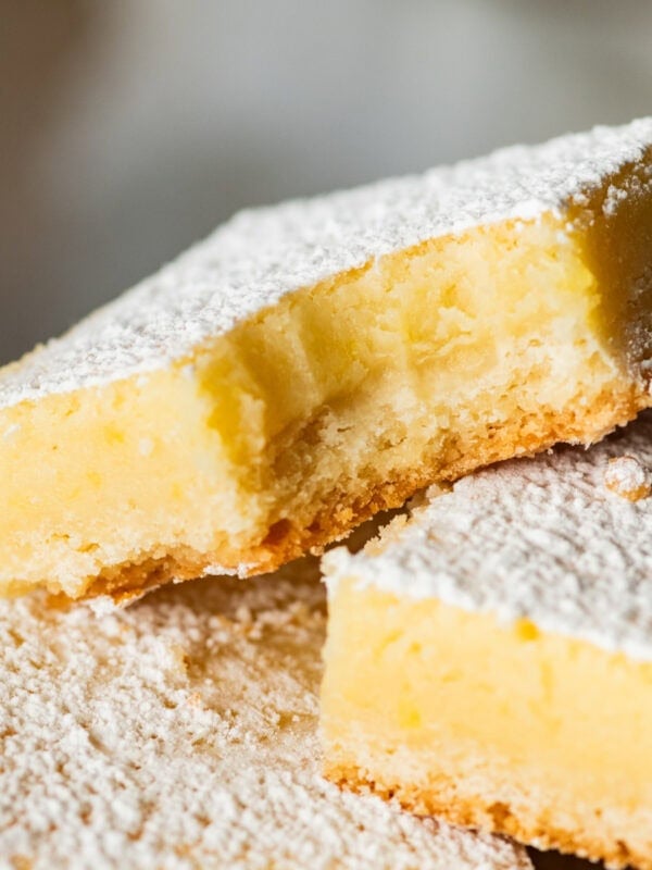 Lemon cream cheese bar with a bite taken out, laying on top of more bars.