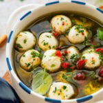 Marinated mozzarella balls in a bowl with ingredients in background.