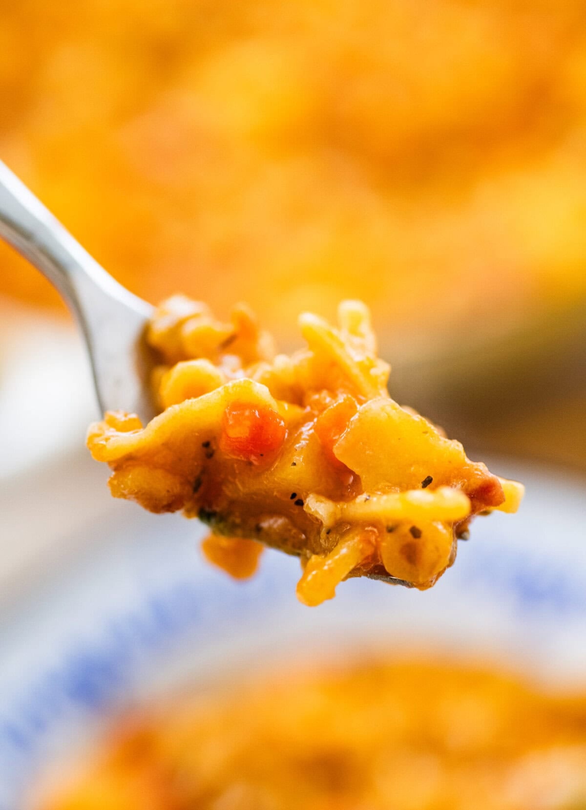 A fork holding up one bite of the recipe over a bowl.