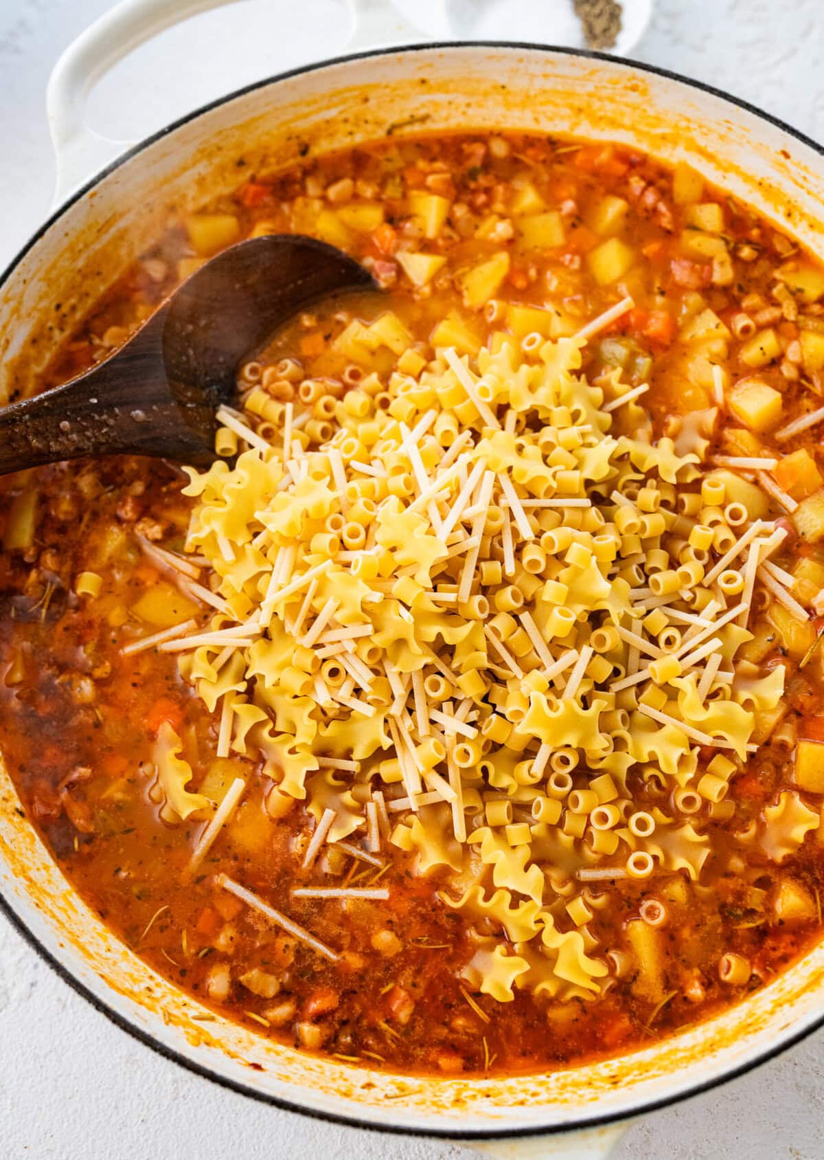 Pasta added to the pot, being stirred in by a wooden spoon. 