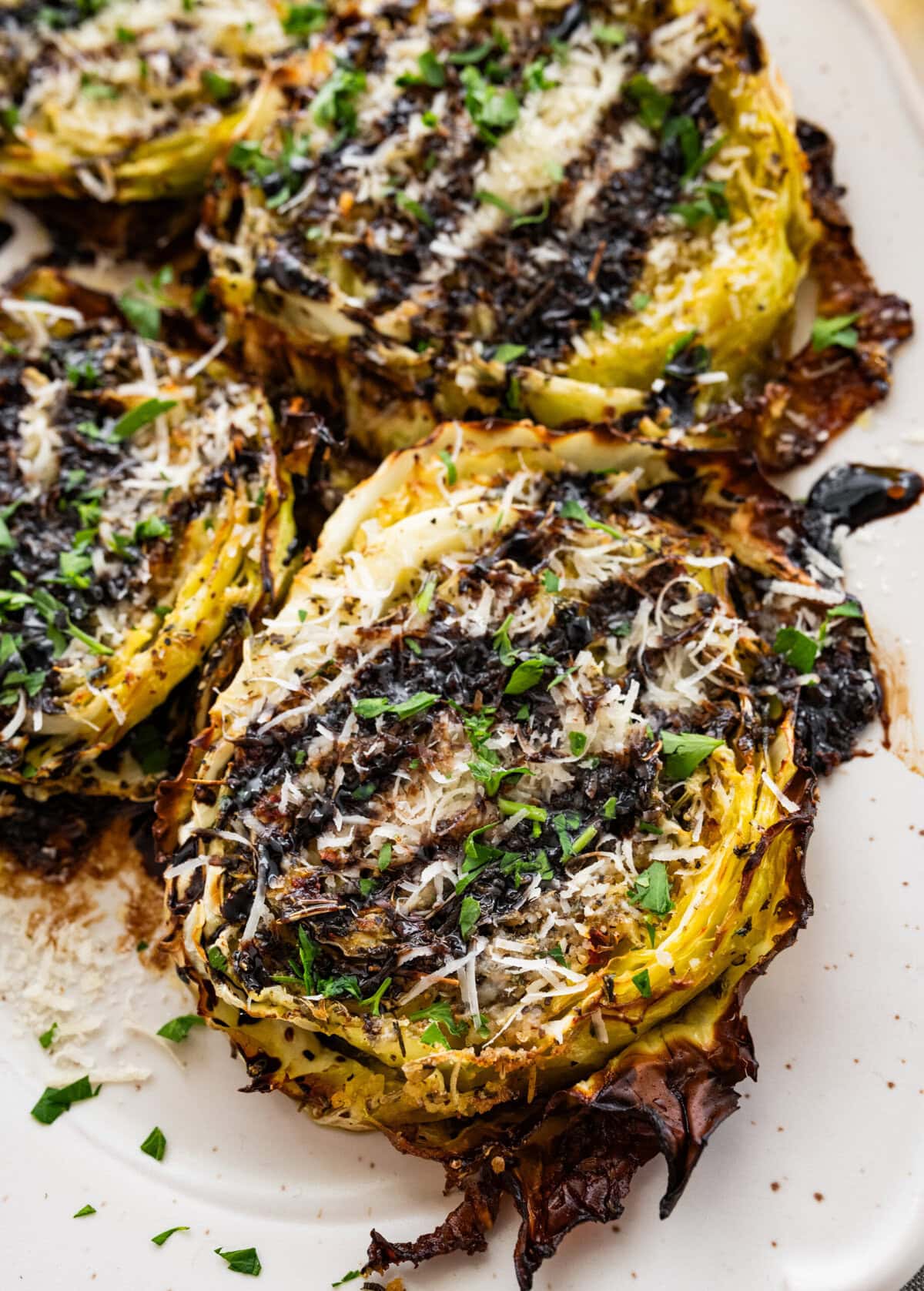 Roasted cabbage steaks drizzled with balsamic glaze, served on a plate.