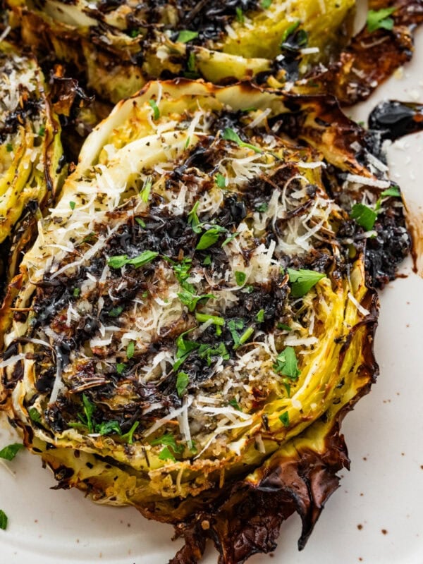 Roasted cabbage steaks drizzled with balsamic glaze, served on a plate.