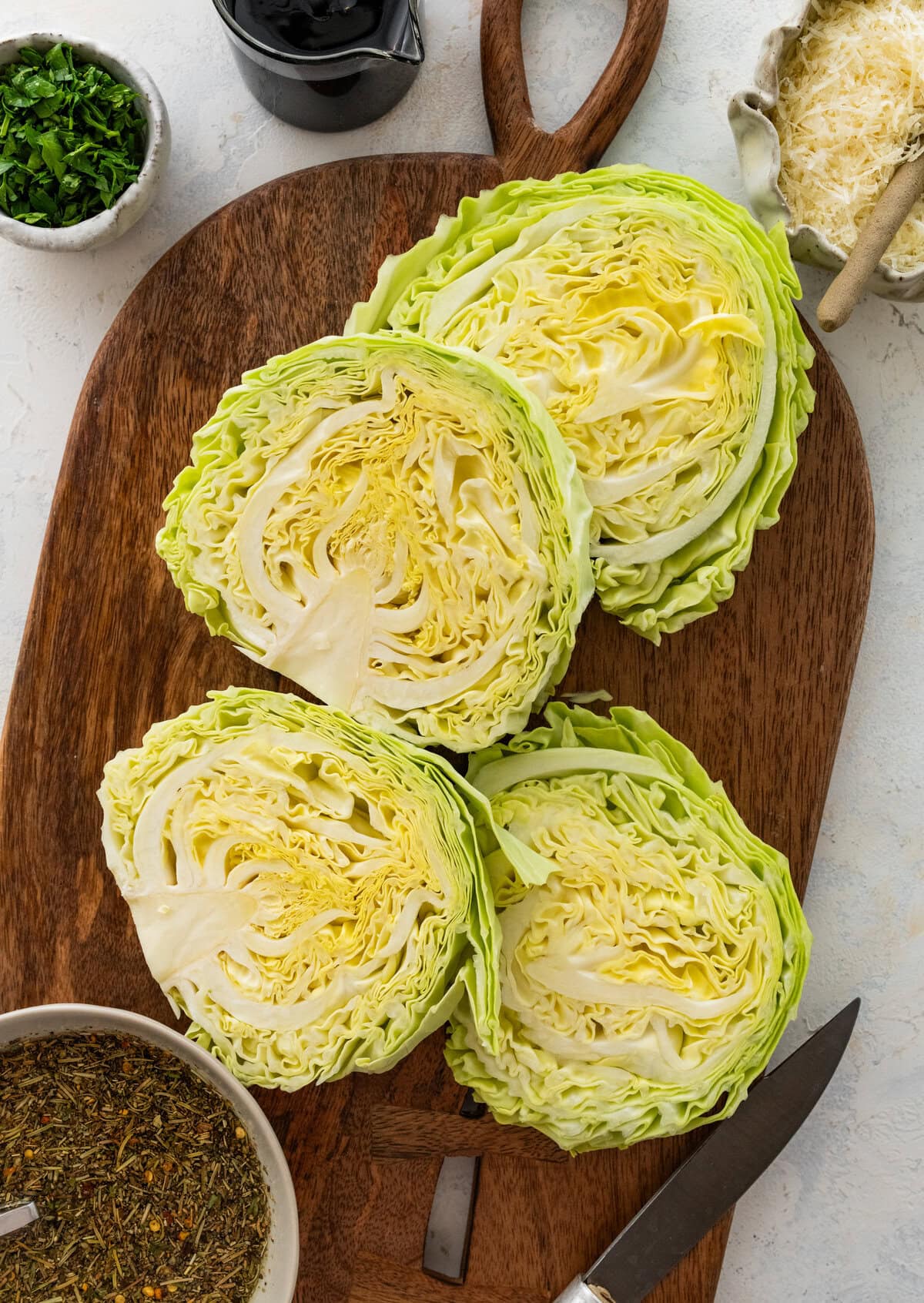 Slices of cabbage laid on a cutting board, with the rest of the ingredients for the recipe nearby.