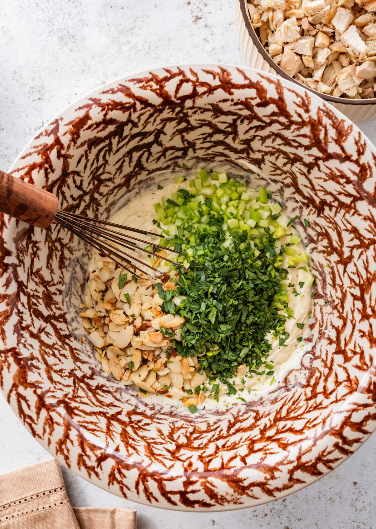 Celery, almonds, and tarragon added to the bowl of dressing.