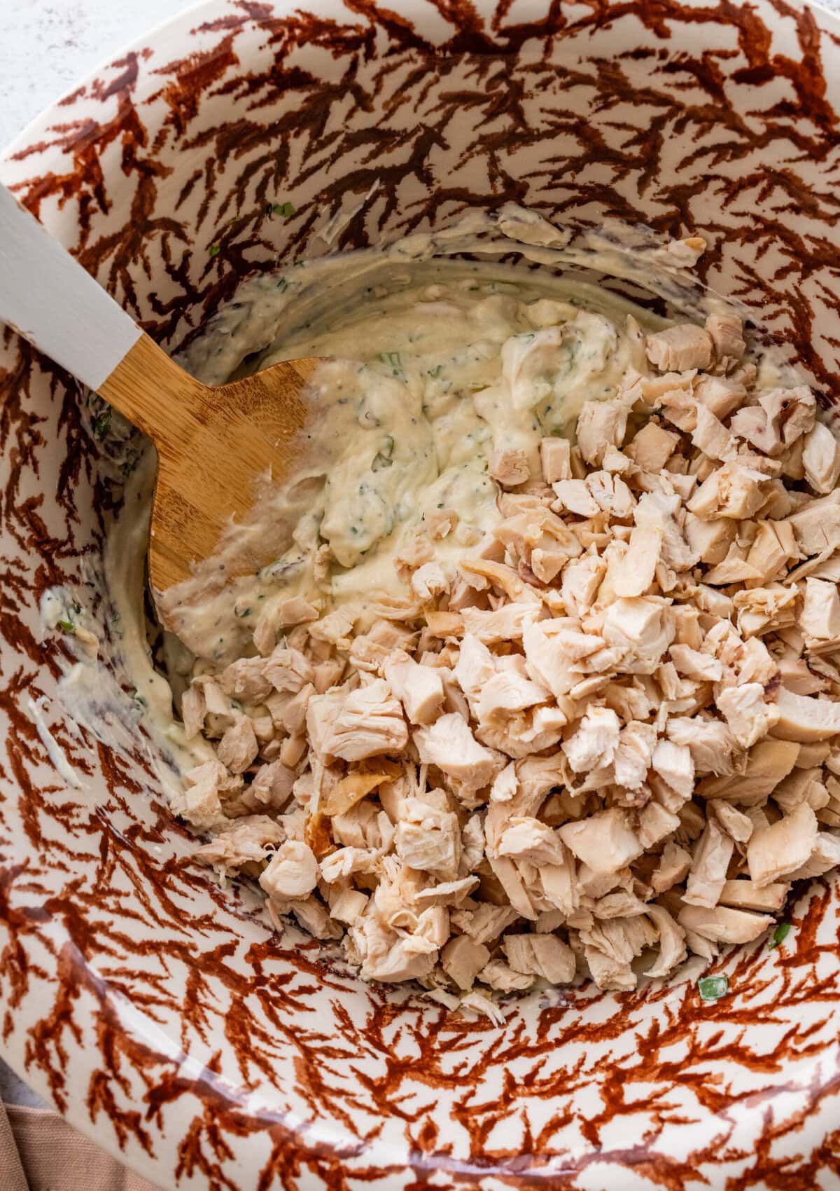 Diced chicken added to the bowl of dressing.