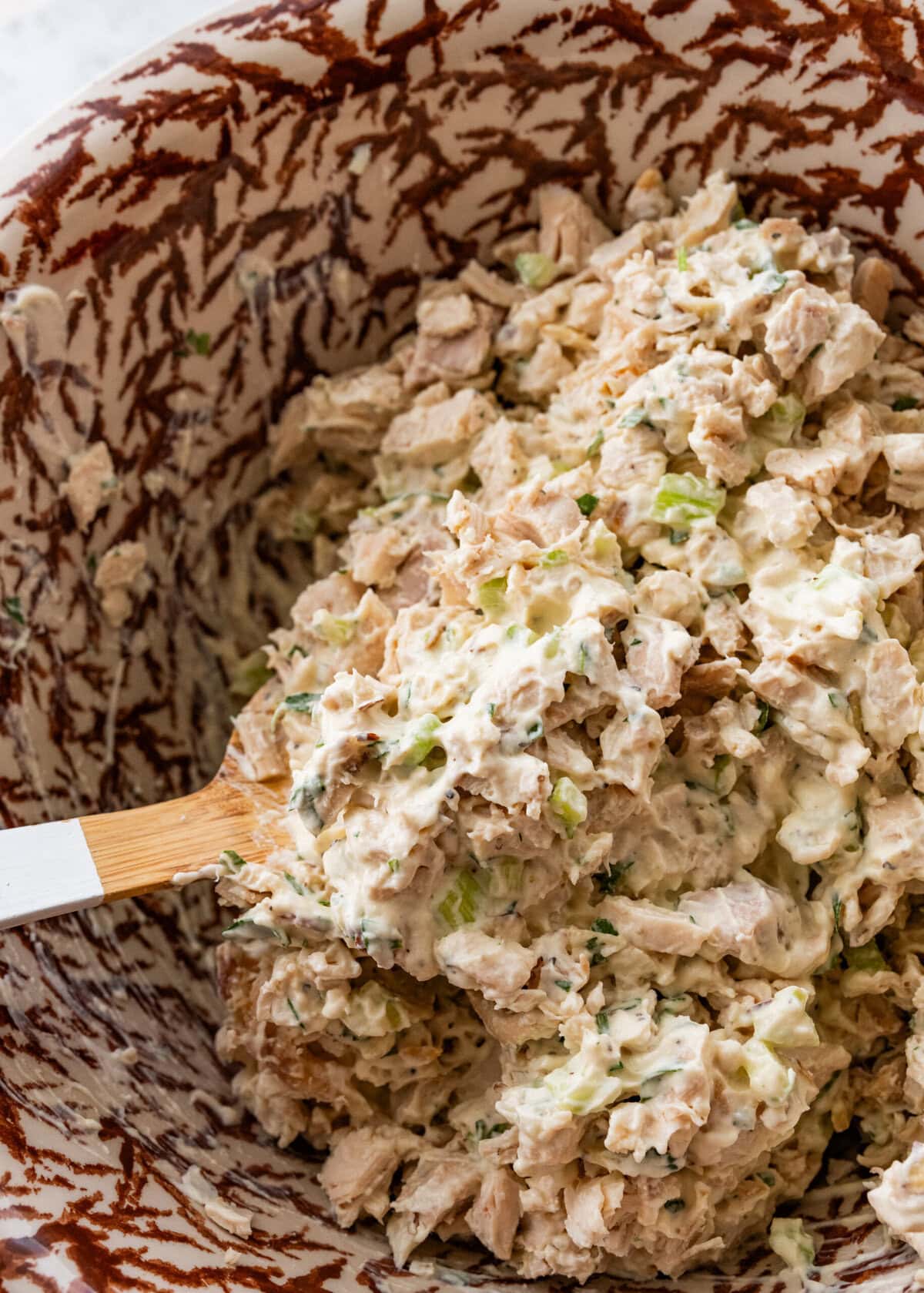 Spoon stirring together the dressing and chicken.