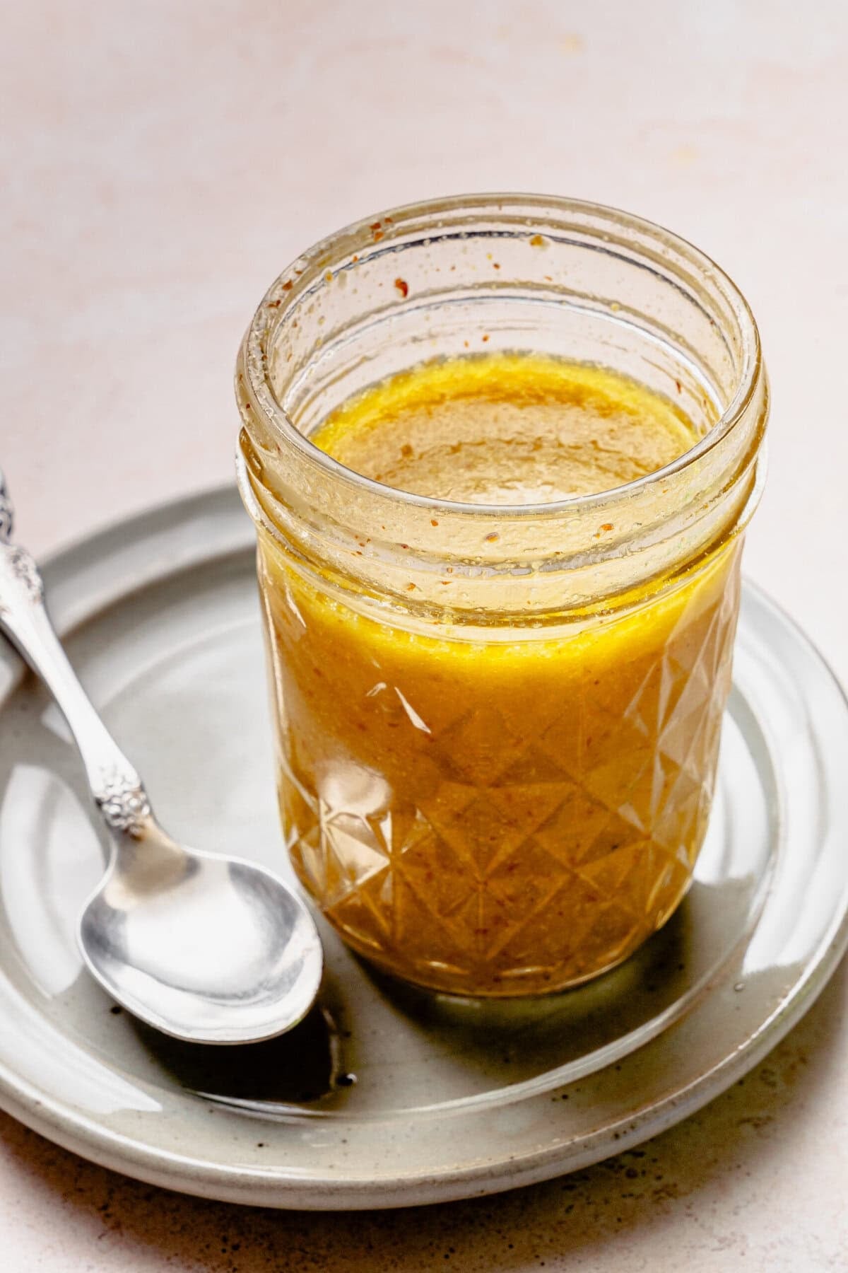 A jar of the dressing after completely combined with a spoon nearby.