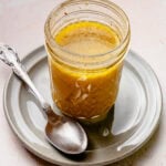 A jar of the dressing after completely combined with a spoon nearby.