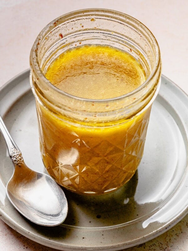 A jar of the dressing after completely combined with a spoon nearby.
