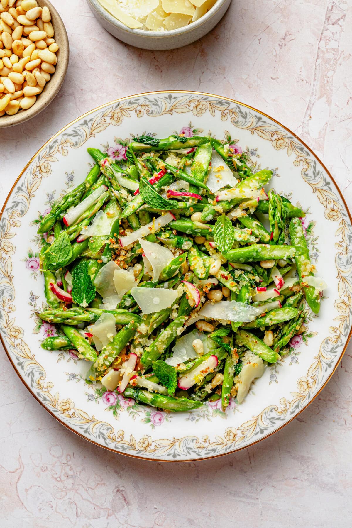 Asparagus salad on a dish with breadcrumbs nearby in a bowl.