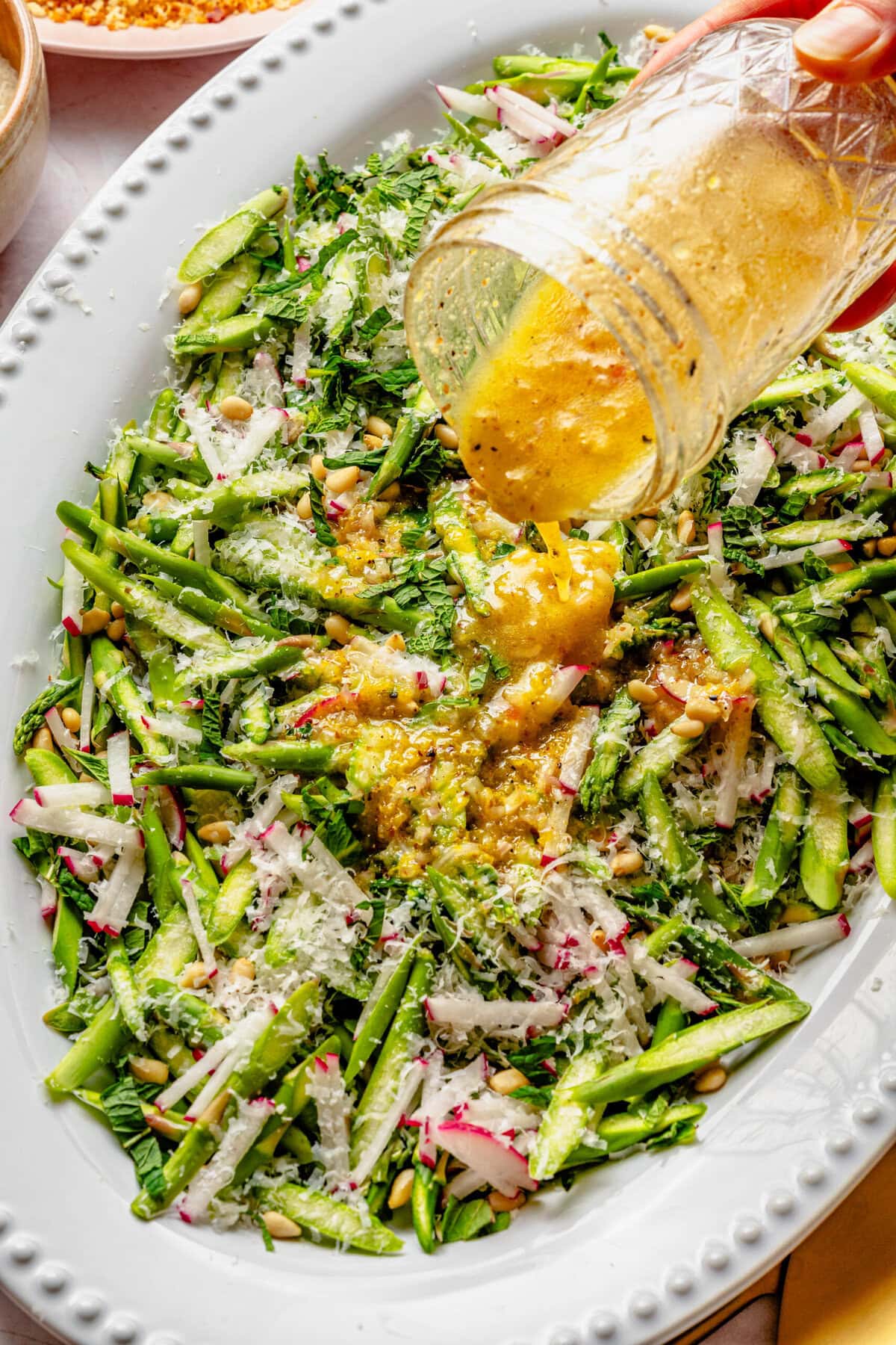 Pouring dressing over the asparagus salad.
