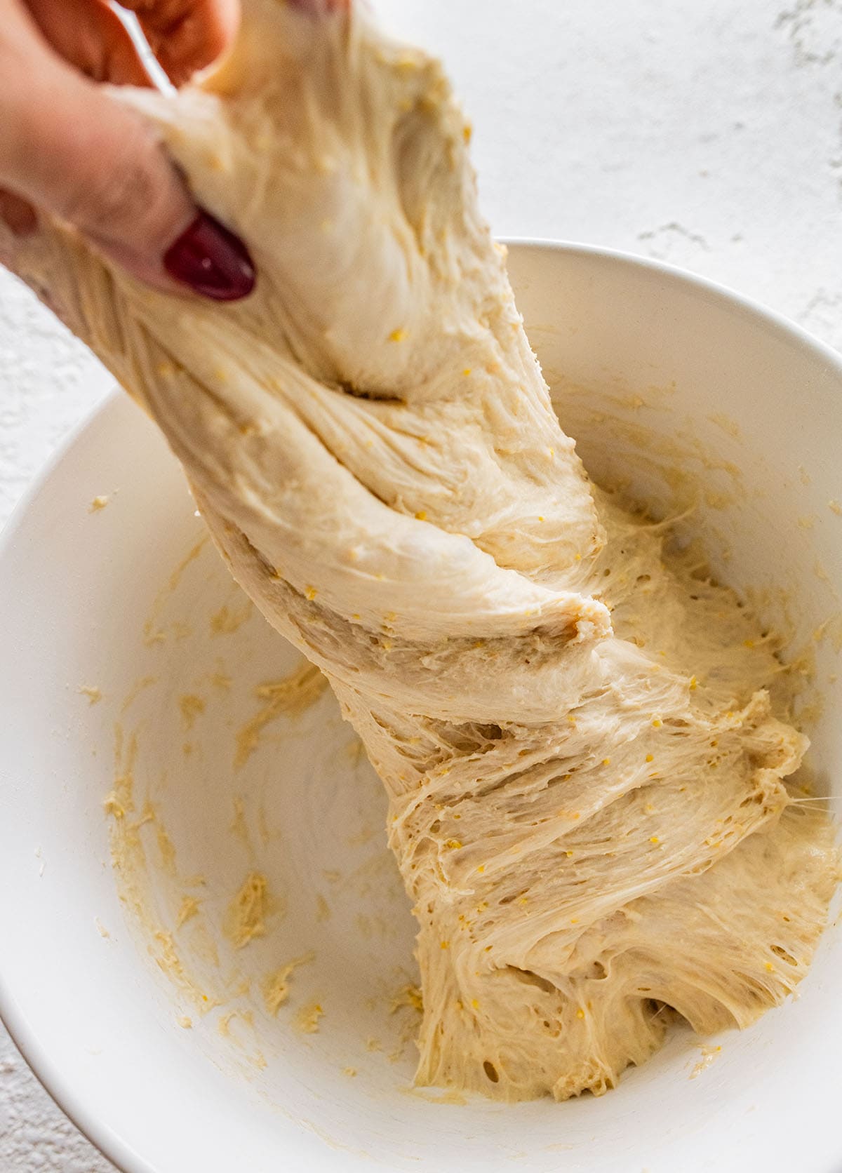 stretching and folding the ciabatta dough in a bowl.