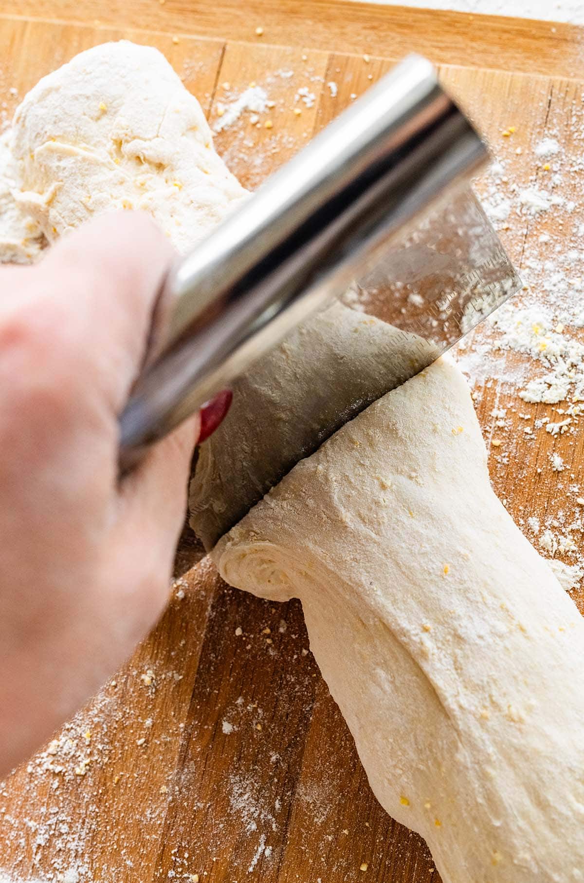 cutting the ciabatta dough into loaves with a bench scraper.