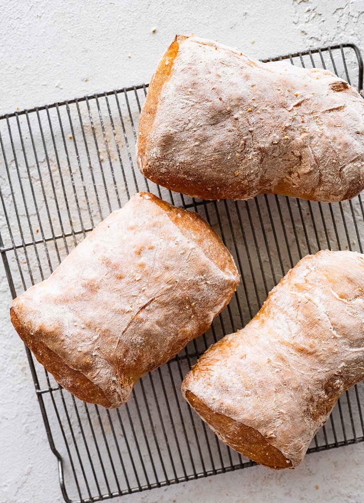 baked ciabatta loaves on a wire cooling rack.